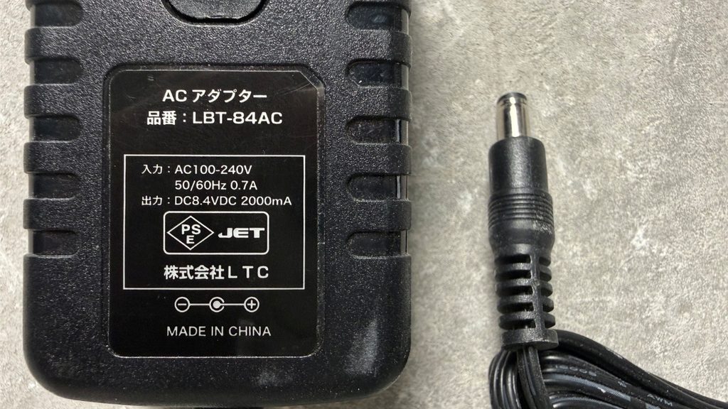 ACアダプターの入力・出力表示と丸型DCプラグ。出力DC8.4V・2000mA、センタープラスの極性マーク